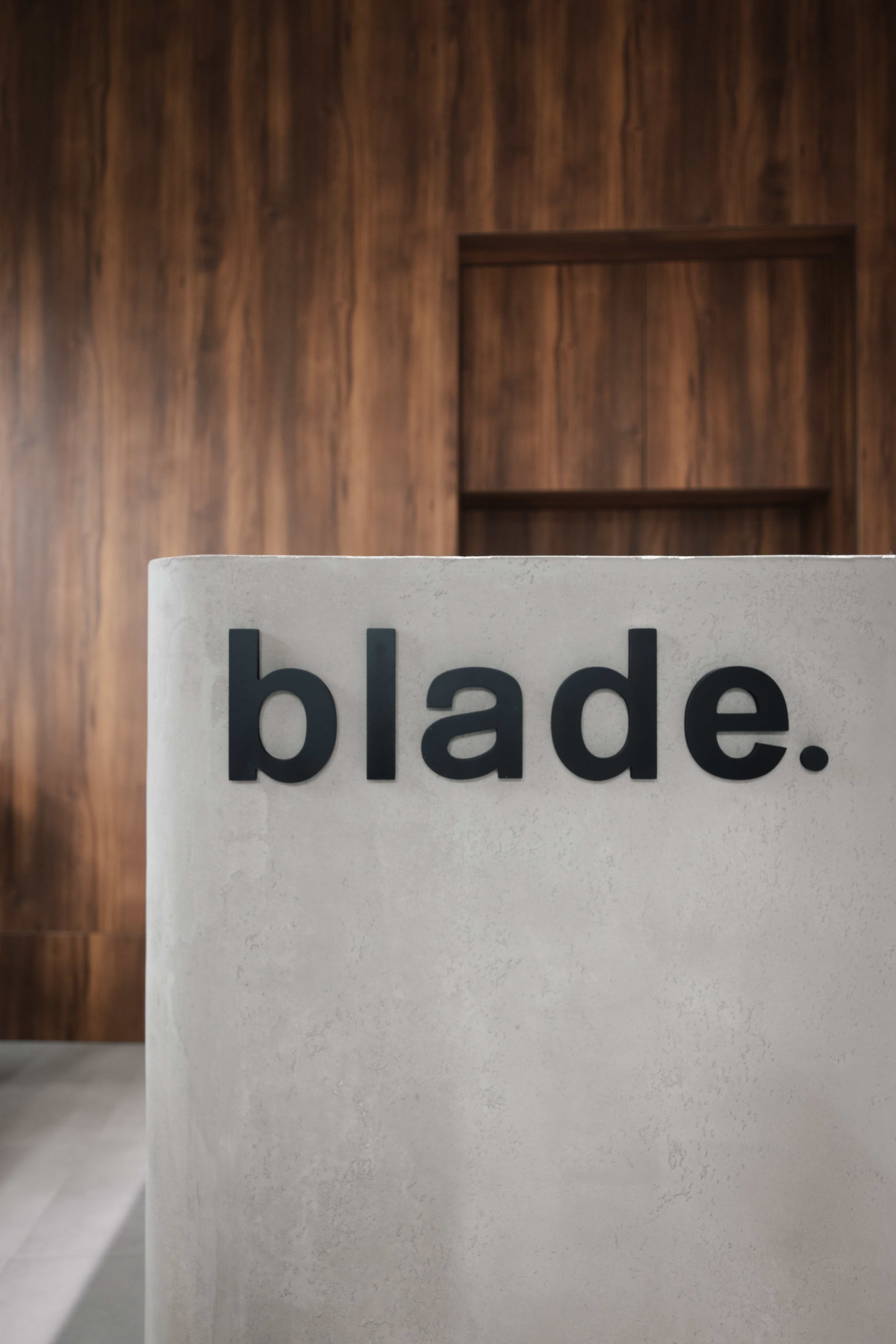 Logo Blade Barbershop na betonové recepci